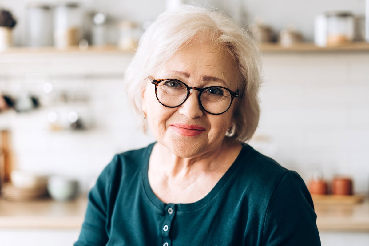 Cheerful senior woman smiling in her bright, modern kitchen